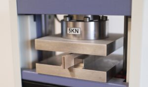 Kartonstück eingeklemmt zwischen zwei metallenen Platten.